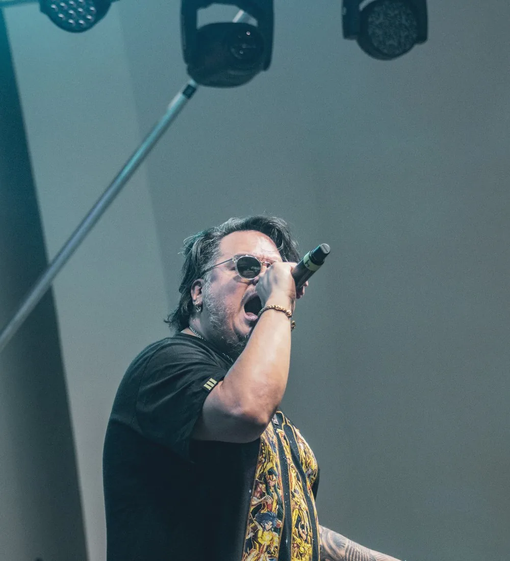 A performer singing into a microphone under stage lights.