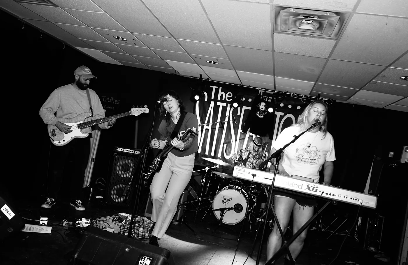 A four-piece band performing on a small DIY venue stage